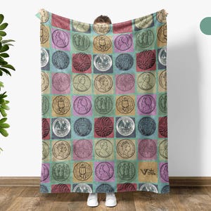 May include: A large, rectangular blanket featuring a repeating pattern of vintage coin illustrations set against a colorful, checkered background. The coins are in squares of various colors, including red, blue, and yellow. The blanket is held up by a person.