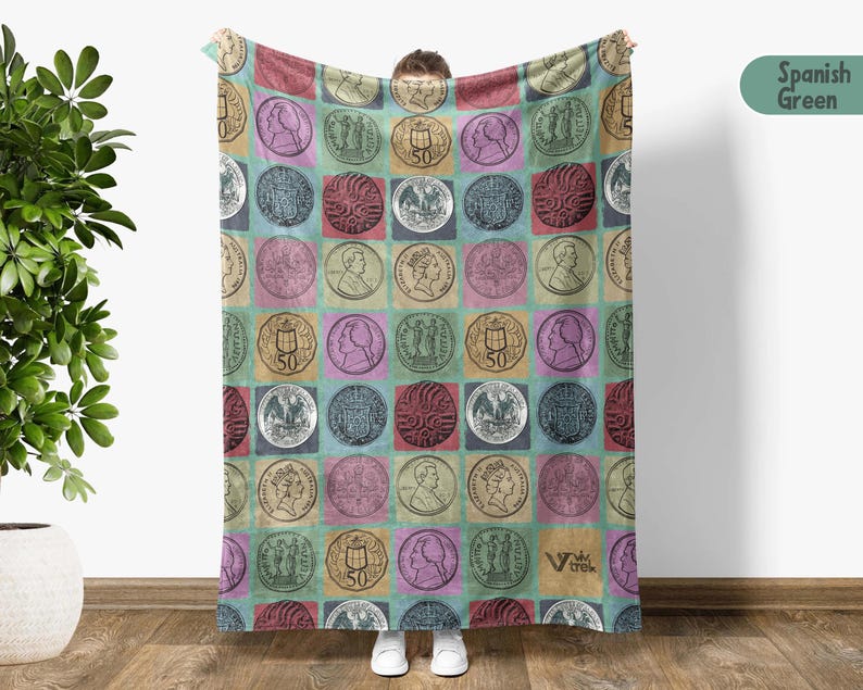 May include: A large, rectangular blanket featuring a repeating pattern of vintage coin illustrations set against a colorful, checkered background. The coins are in squares of various colors, including red, blue, and yellow. The blanket is held up by a person.