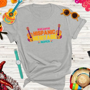 May include: A gray t-shirt with the text "National Hispanic Heritage Month" and a colorful guitar graphic.