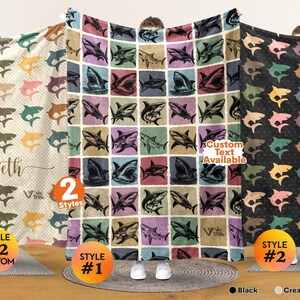 May include: Three blankets featuring shark patterns. The left blanket is cream with a checkered pattern and the name Elizabeth. The center blanket has a grid of various shark illustrations. The right blanket is black with a repeating shark print.