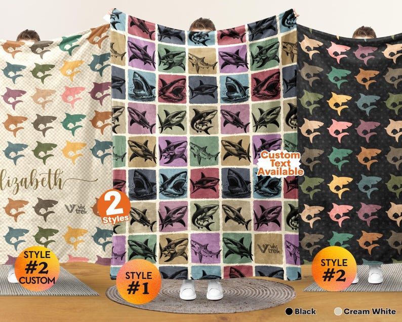 May include: Three blankets featuring shark patterns. The left blanket is cream with a checkered pattern and the name Elizabeth. The center blanket has a grid of various shark illustrations. The right blanket is black with a repeating shark print.
