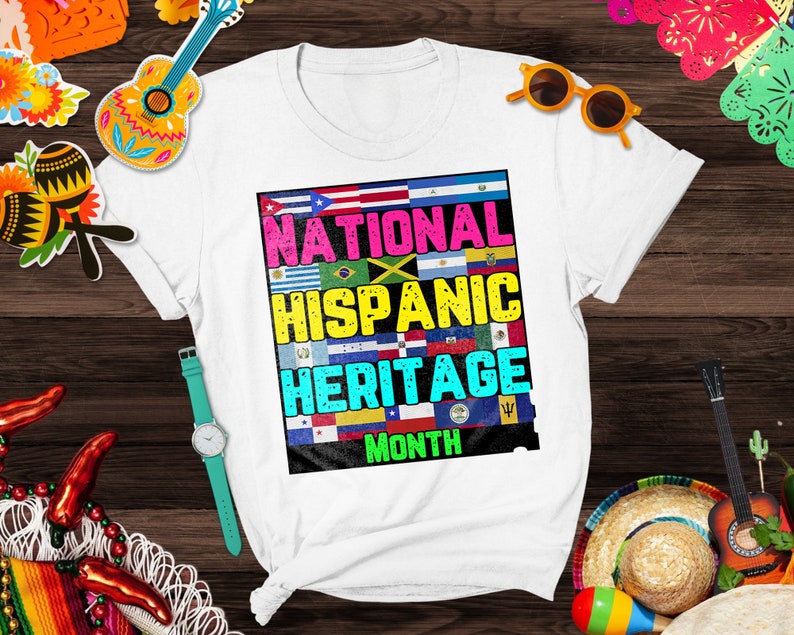 May include: White t-shirt with a colorful graphic design featuring flags of various Hispanic countries. The graphic reads "National Hispanic Heritage Month".