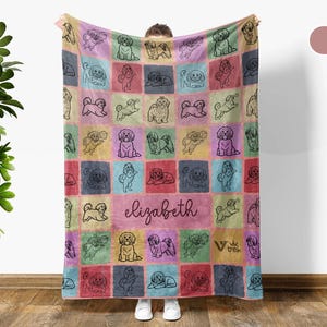 May include: A colorful blanket featuring a patchwork design with various dog illustrations in different poses. The blanket has a pink central panel with the name "Elizabeth" in cursive. The squares are in shades of pink, blue, green, yellow, and red.