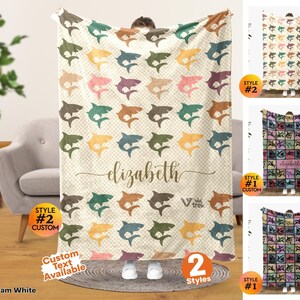 May include: A rectangular throw blanket featuring a repeating pattern of sharks in various muted colors on a cream-colored checkered background. The center displays the name elizabeth in cursive script, with the text V trek printed below it.