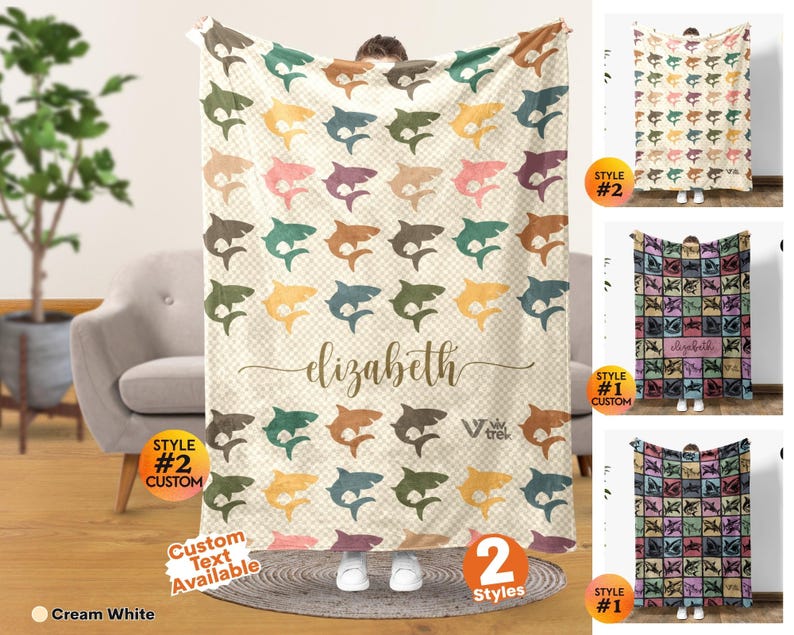 May include: A rectangular throw blanket featuring a repeating pattern of sharks in various muted colors on a cream-colored checkered background. The center displays the name elizabeth in cursive script, with the text V trek printed below it.