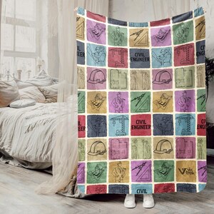 May include: A colorful throw blanket featuring a patchwork design with squares of various colors. Each square contains line drawings of civil engineering tools and figures, with the words "CIVIL ENGINEER" in some squares. The blanket is draped over a bed.