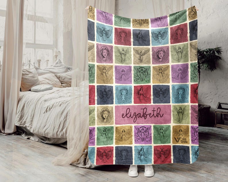 May include: A rectangular throw blanket featuring a grid of colorful squares, each displaying a unique line-art illustration of an angel. The center square contains the name elizabeth in cursive script, and the bottom right corner features a small logo.