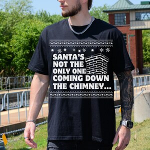 K&ouml;nnte beinhalten: Schwarzer Weihnachtspullover mit einem wei&szlig;en Motiv einer gemauerten Kamin und dem Text "Santa's not the only one coming down the chimney..."