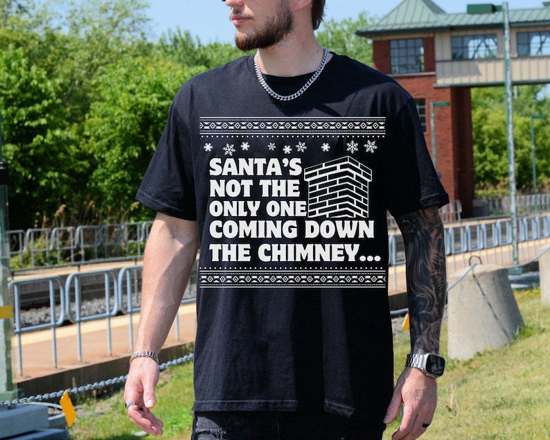 K&ouml;nnte beinhalten: Schwarzer Weihnachtspullover mit einem wei&szlig;en Motiv einer gemauerten Kamin und dem Text "Santa's not the only one coming down the chimney..."