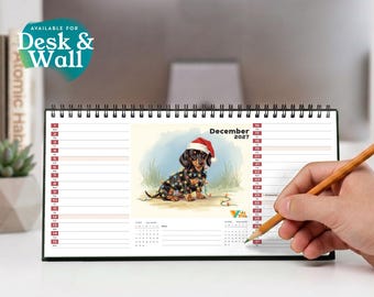 May include: A horizontal desk calendar for December 2027 featuring a black and tan dachshund wearing a red Santa hat and wrapped in colorful Christmas lights. The calendar includes a grid for dates and the text Available for Desk & Wall.
