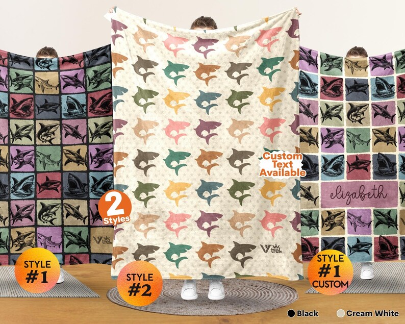 May include: Three rectangular blankets featuring shark patterns. The left blanket has a grid of colorful shark illustrations on a dark background. The center blanket is cream white with repeating shark silhouettes. The right blanket shows a grid with the name elizabeth.