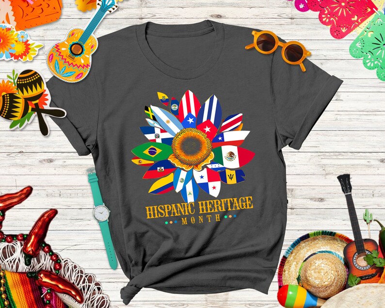 May include: A dark gray t-shirt with a sunflower design made up of flags from different Hispanic countries. The text "HISPANIC HERITAGE MONTH" is printed below the sunflower.