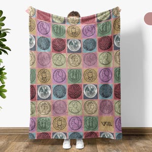 May include: A colorful blanket featuring a repeating pattern of vintage coin illustrations in square blocks. The coins are in various colors, including green, pink, and blue, set against a multi-colored background. The blanket has a soft, cozy appearance.