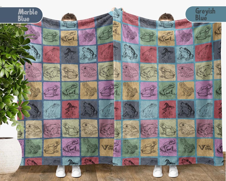 Puede incluir: Una manta de felpa suave y mullida con un patr&oacute;n repetido de ranas en varias poses. La manta est&aacute; en un esquema de color azul y rosa con un sutil efecto de m&aacute;rmol. El texto "Marble Blue" y "Greyish Blue" est&aacute; impreso en las esquinas superiores de la manta.