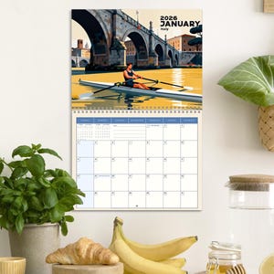 May include: A 2026 January calendar featuring a vibrant illustration of a rower on a river in Italy. The calendar has a spiral binding and a grid layout for daily planning. The image includes a bridge and the text "2026 January Italy".