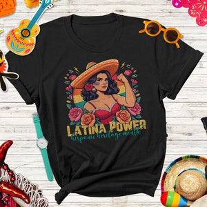 May include: Black t-shirt with a retro-style illustration of a woman wearing a sombrero and a red top. The text "Latina Power" and "Hispanic Heritage Month" is printed on the shirt.