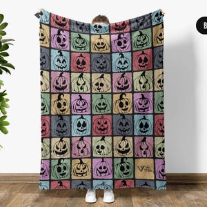 May include: A rectangular throw blanket featuring a grid pattern of colorful squares, each containing a black silhouette of a jack-o'-lantern pumpkin. The background colors include shades of pink, blue, yellow, and green. The text Viv Trek is visible.