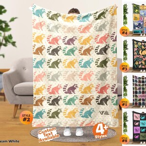 May include: A cream white throw blanket featuring a repeating pattern of raccoons in various colors including yellow, pink, teal, and brown. The blanket includes the text V trek and Custom Text Available. Four additional blanket styles are shown on the right.