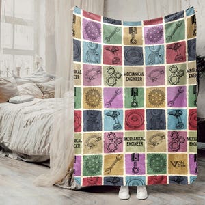 May include: A colorful blanket with a patchwork design featuring mechanical engineering tools and gears. The squares are in various colors, with the words "MECHANICAL ENGINEER" printed on some. The blanket is draped over a bed.