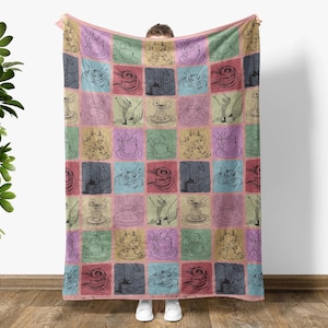 May include: A pink and white throw blanket with a repeating pattern of hands forming pottery on a pottery wheel. The pattern is in black and white line art.