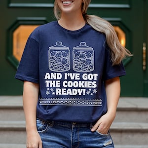 K&ouml;nnte beinhalten: Ein marineblaues T-Shirt mit einer wei&szlig;en Grafik von zwei mit Keksen gef&uuml;llten Keksdosen. Der Text auf dem Shirt lautet "And I've got the cookies ready!"