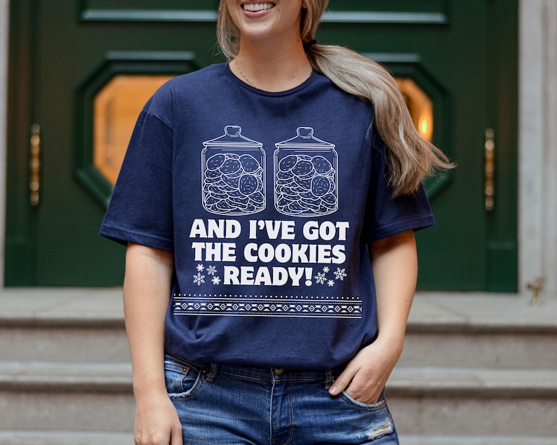 K&ouml;nnte beinhalten: Ein marineblaues T-Shirt mit einer wei&szlig;en Grafik von zwei mit Keksen gef&uuml;llten Keksdosen. Der Text auf dem Shirt lautet "And I've got the cookies ready!"