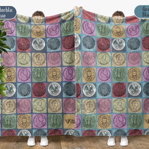 May include: A blanket with a repeating pattern of vintage coins in various colors, including blue, pink, and gold. The coins are set against a grid of squares, creating a patchwork effect. The blanket is held up by a person.