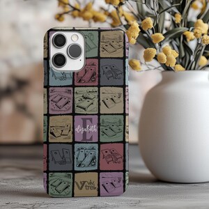 Könnte beinhalten: Eine Smartphone-Hülle mit einem Gittermuster aus Cornhole-Spiel-Illustrationen in gedeckten Blau-, Grün- und Rottönen. Das mittlere Quadrat zeigt den Buchstaben E und den Namen Elizabeth in weißer Schreibschrift sowie den Text viv trek.