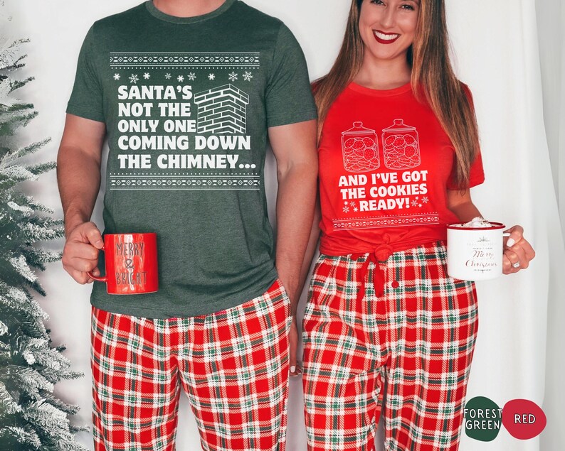 K&ouml;nnte beinhalten: Ein Paar tr&auml;gt passende Weihnachtspyjamas. Der Mann tr&auml;gt ein gr&uuml;nes T-Shirt mit dem Text "Santa's not the only one coming down the chimney..." und eine rot-gr&uuml;ne karierte Schlafhose. Die Frau tr&auml;gt ein rotes T-Shirt mit dem Text "And I've got the cookies ready!" und eine rot-gr&uuml;ne karierte Schlafhose.