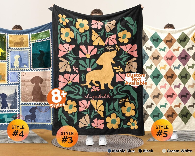 May include: Three rectangular blankets featuring dachshund designs. The left blanket has blue postage stamp motifs with dachshund silhouettes. The center black blanket displays a large yellow dachshund surrounded by pink and yellow flowers with the text elizabeth. The right blanket has a cream-colored diamond pattern with small dachshunds.
