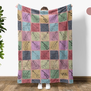 May include: A colorful blanket featuring a repeating pattern of violins and bows within square blocks. The squares are in various pastel colors, including pink, yellow, blue, and purple. The blanket has a soft, inviting appearance.