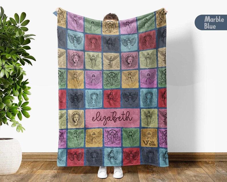 May include: A rectangular throw blanket featuring a grid of colorful squares, each containing a black line-art illustration of an angel. A central horizontal rectangle displays the name elizabeth in cursive script. The blanket has a marble blue color.