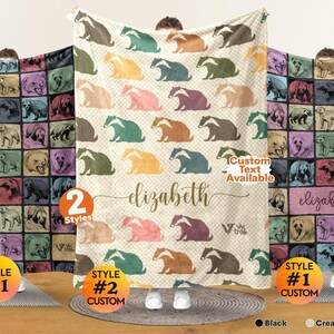 May include: A rectangular fleece blanket featuring a repeating pattern of badger illustrations in various colors. The center blanket has a cream white background with the name elizabeth printed in cursive script and the text Custom Text Available.