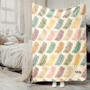 May include: A cream-colored blanket with a repeating pattern of bacon strips in various colors, including pink, brown, and green. The blanket has a soft, inviting appearance and is suitable for a bed or couch.