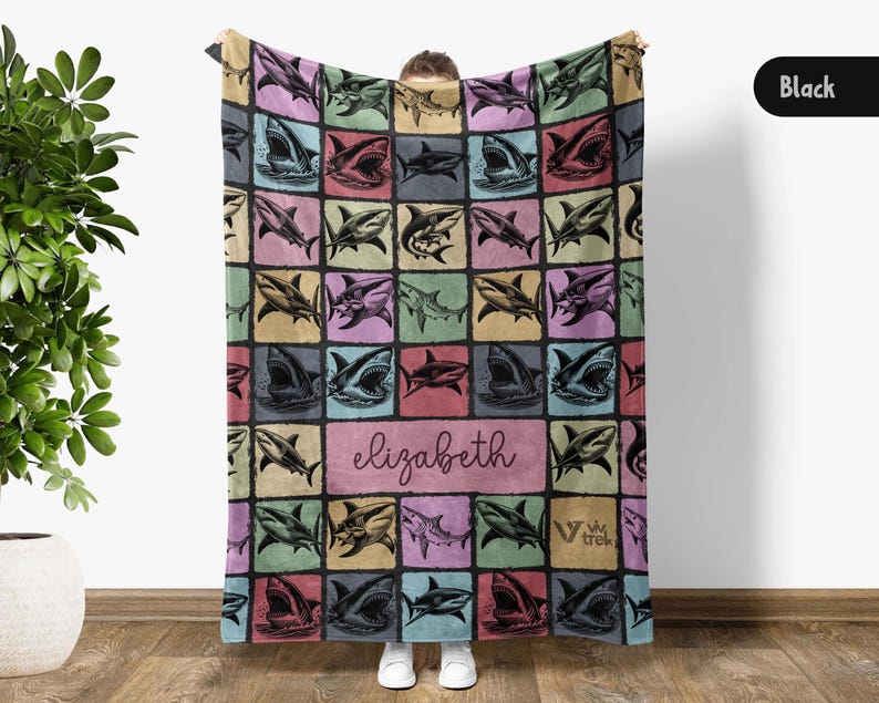 Może przedstawiać: Kolorowy koc z powtarzającym się wzorem ilustracji rekin&oacute;w. Koc ma spersonalizowaną sekcję z imieniem "Elizabeth" w kursywie. Tło to patchwork kwadrat&oacute;w w pastelowych odcieniach.