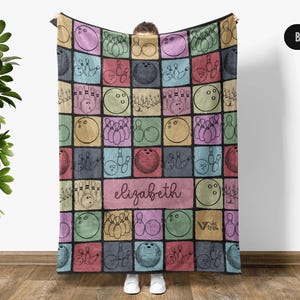 May include: A black blanket featuring a colorful bowling-themed design. The blanket has a grid pattern with bowling balls, pins, and the name "Elizabeth" in a pink rectangle. The design is in various colors including pink, blue, green, and yellow.