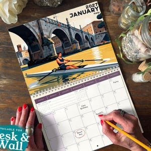 May include: A 2027 January wall calendar featuring an illustration of a person rowing a boat on a river under a stone bridge in Italy. The calendar grid includes handwritten notes for the 15th, 23rd, and a circled date. The page is spiral bound.