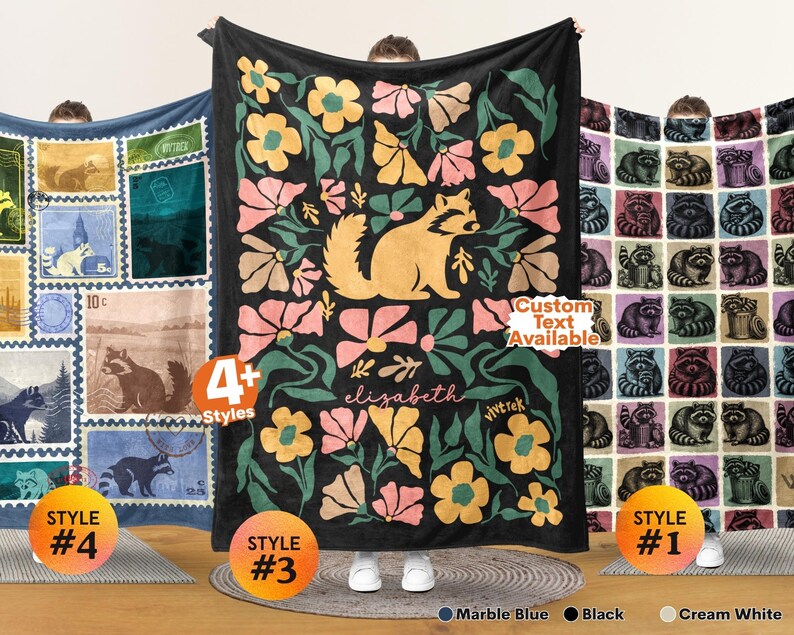 May include: Three rectangular blankets featuring raccoon designs. The left blanket has a postage stamp grid pattern. The center black blanket displays a large raccoon surrounded by pink and yellow flowers with the name elizabeth. The right blanket has a grid of raccoon illustrations. Text includes 4+ Styles, Custom Text Available, and vivtrek.