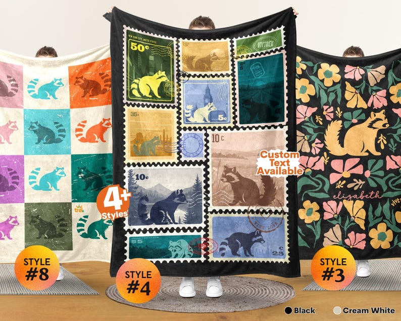 May include: Three rectangular blankets featuring raccoon designs. The left blanket has a grid of colorful raccoons. The center black blanket displays a collage of vintage-style postage stamps with raccoon illustrations. The right blanket shows a floral pattern with a central raccoon and the name Elizabeth.