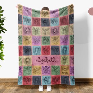 May include: A rectangular fleece blanket featuring a grid of squares with various angel illustrations in shades of pink, blue, green, and yellow. The center square displays the name elizabeth in a dark script font. The blanket has a soft texture.