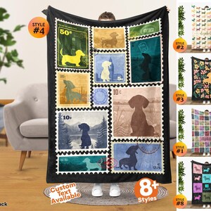 May include: A black fleece blanket featuring a collage of vintage-style postage stamp designs, each displaying a silhouette of a dachshund dog in various colors and settings, including forest, city, and landscape scenes with numerical values.
