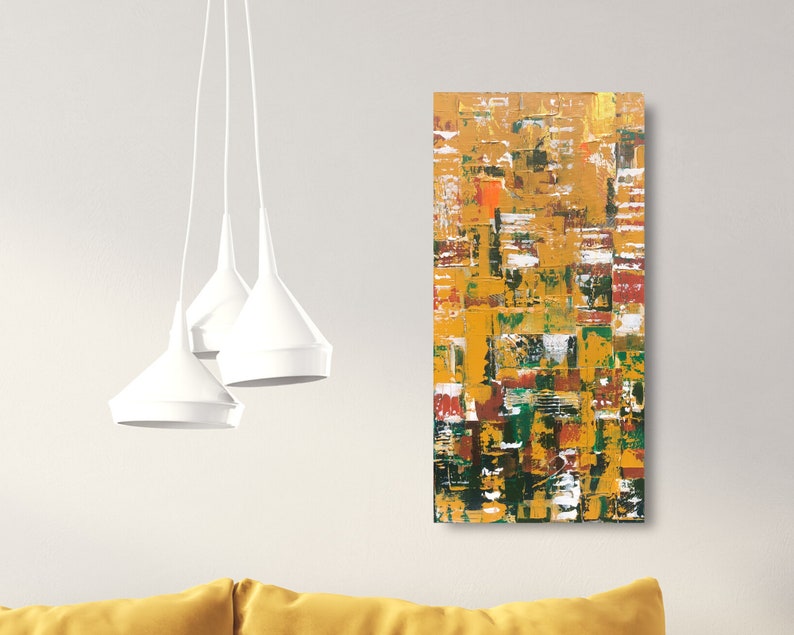 Op de afbeelding: Abstracte kunstschilderij met een textuuroppervlak. Het kunstwerk toont een mix van kleuren, waaronder goud, geel, groen, rood en wit, gerangschikt in een rechthoekige compositie. Het schilderij wordt op een witte muur getoond.