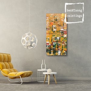 Op de afbeelding: Abstract schilderij met een textuur, met een mix van gele, oranje, rode, groene en witte penseelstreken. Het rechthoekige kunstwerk hangt aan een grijze muur. De tekst "heARTsong paintings" staat rechtsboven.
