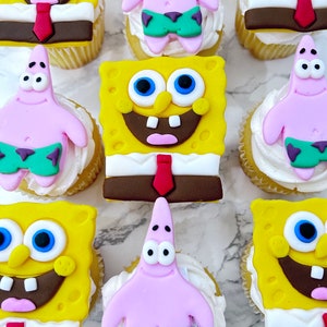 May include: A collection of nine cupcakes decorated with cartoon characters. The cupcakes are yellow with white frosting and feature characters from the cartoon Spongebob Squarepants. There are three Spongebob cupcakes, three Patrick Star cupcakes, and three cupcakes with both Spongebob and Patrick.