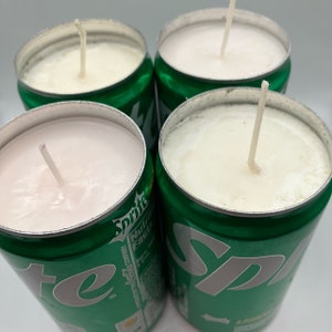 May include: Four handmade candles in repurposed green and silver Sprite soda cans. The candles have a creamy white wax and a single wick. The cans are arranged in a square, with the tops of the candles visible.