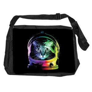 May include: Black messenger bag with a cat in an astronaut helmet. The cat's face is visible through the helmet's visor, with a colourful galaxy design inside. The helmet has a rainbow-coloured trim. The bag has a black adjustable strap.