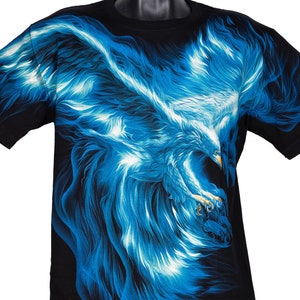 Puede incluir: Camiseta negra con un gráfico de águila azul y blanco. El águila está representada en un diseño arremolinado y ardiente.