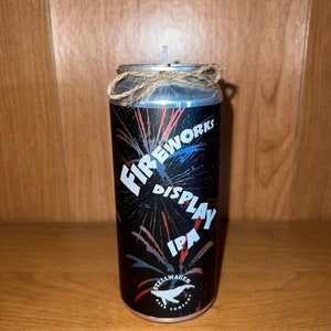 May include: A silver can candle with a black and white design featuring fireworks and the text "Fireworks Display IPA" and the logo "Stellwagen Beer Company".