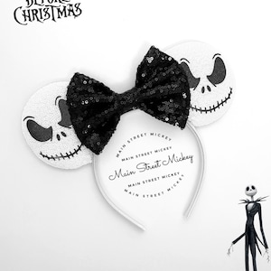 May include: White headband with black sequin bow and two white ears featuring a black and white Jack Skellington face from the movie Nightmare Before Christmas. The headband has the text "Main Street Mickey" printed on it.