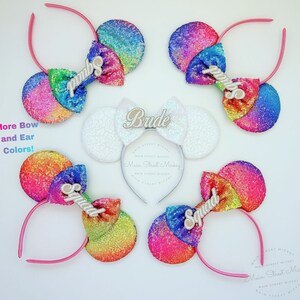 Puede incluir: Conjunto de cinco orejas de Minnie Mouse con lentejuelas arcoíris con diferentes textos en cada lazo. Los textos incluyen "Bride", "Squad" y "pimbo".